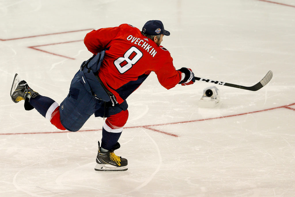 хоккеист бьет по шайбе